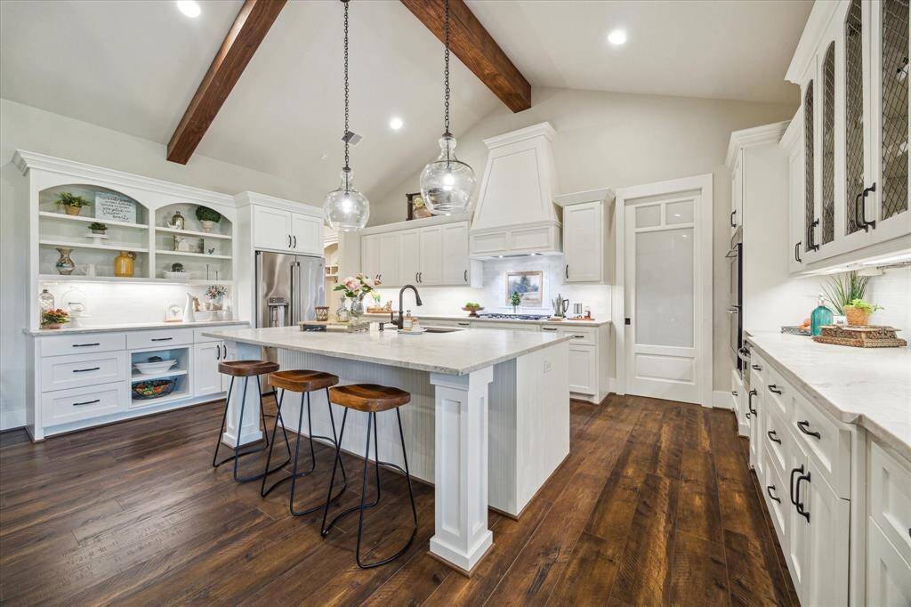 A large central island offers bar seating, deep drawers, and pendant lighting that brings warmth to the heart of the home.