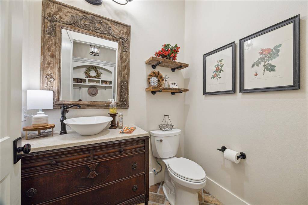Rustic-chic powder room with a carved wood mirror, vessel sink, and timeless vintage detailing right off the mudroom, laundry, and kitchen.