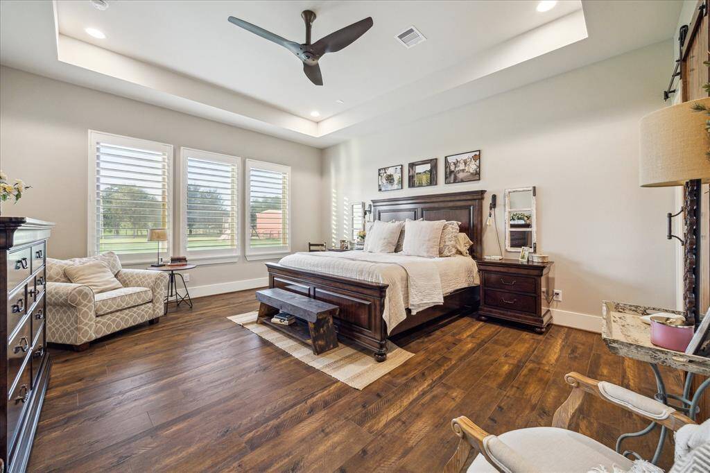 Spacious and serene owner’s suite with wall-to-wall windows overlooking the property’s peaceful acreage.