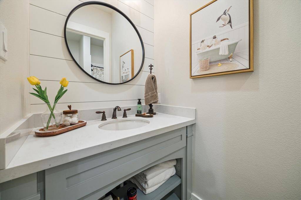 Guest bath with playful charm, custom mirror, and shiplap walls - proof that every space has been lovingly designed.