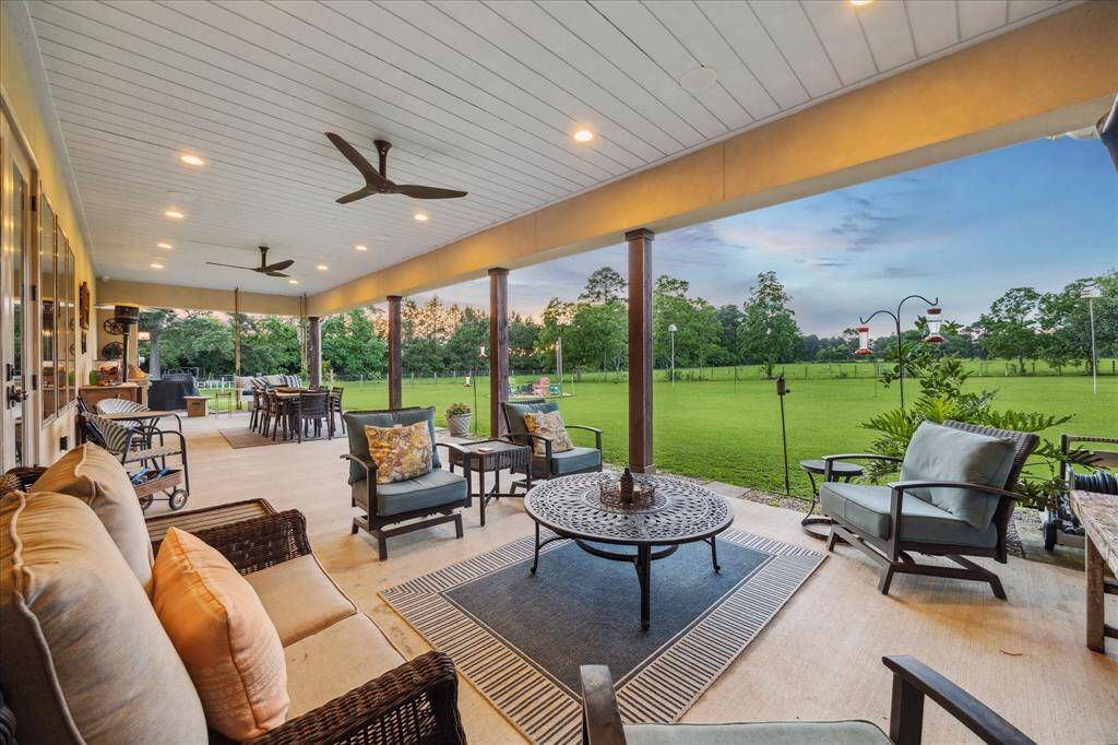 Generous covered patio with ceiling fans, recessed lighting, and multiple seating zones for every moment of the day.