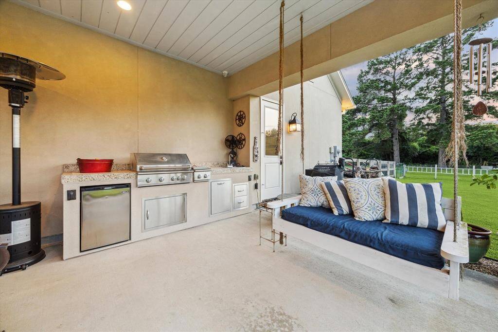 Covered outdoor kitchen with built-in grill, prep space, and cozy porch swing - entertaining and relaxing made easy.