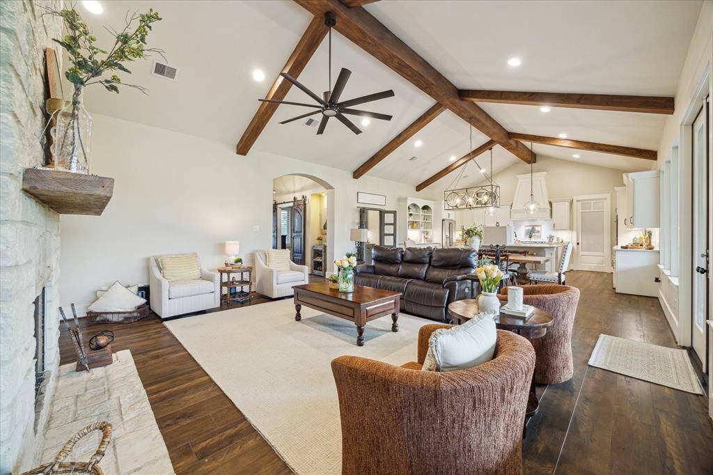 Vaulted ceilings with exposed beams elevate the space while oversized windows offer peaceful views of the backyard and acreage beyond.