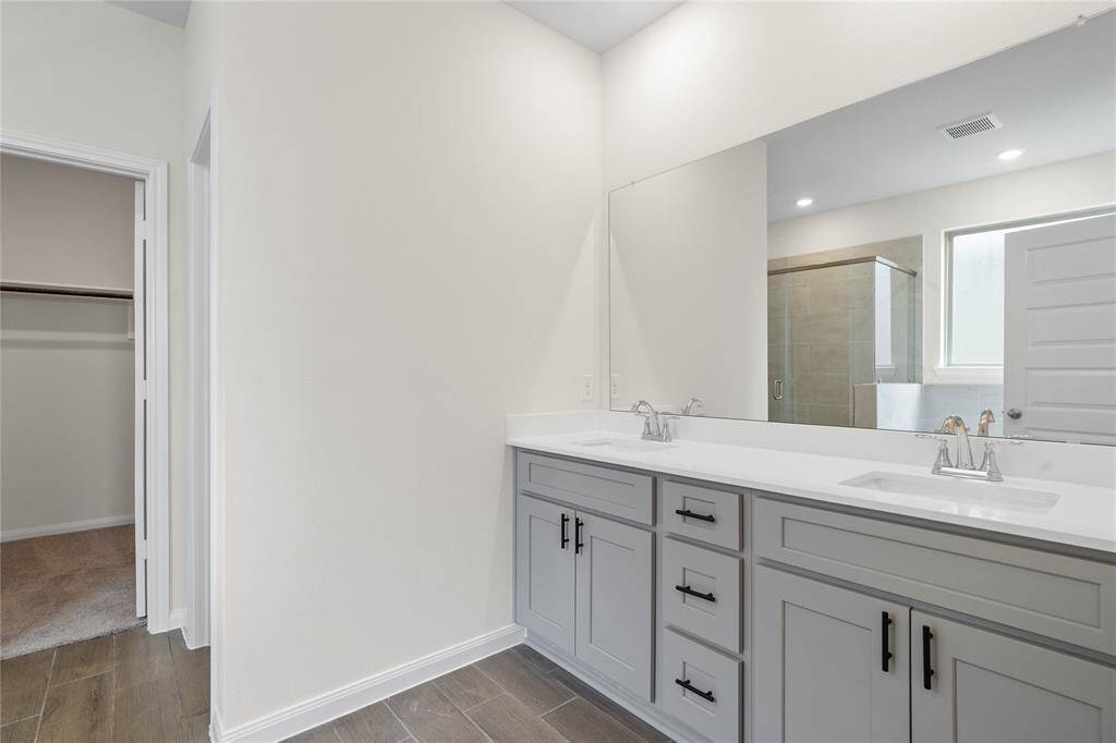 This primary bathroom is definitely move-in ready! Featuring an oversized walk-in shower with tile surround, separate garden tub for soaking after a long day with custom tile detailing, neutral stained cabinets with light countertop and dual vanities, spacious walk-in closet with shelving, high ceilings, neutral paint, sleek and modern finishes.
