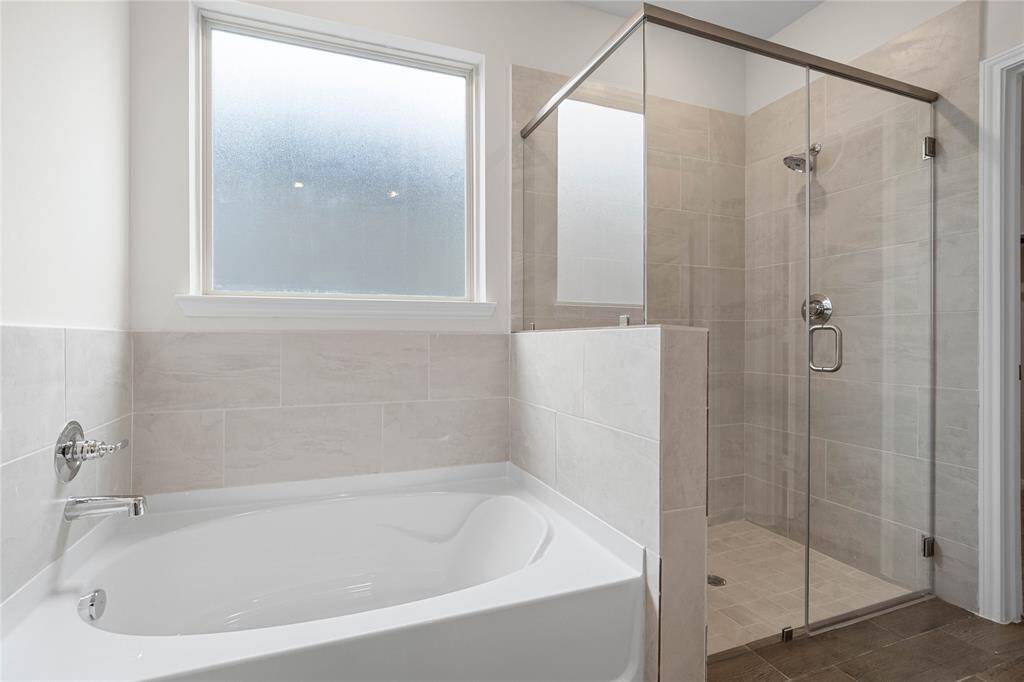 Additional view of the primary bathroom featuring the large garden tub with custom tile detailing and the walk in shower with tile surround.