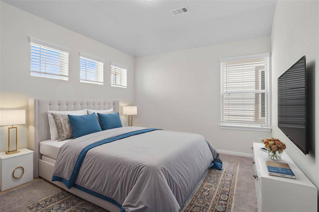 Secondary bedroom features plush carpet, neutral paint, raised ceilings, closet space, and large windows with blinds. *virtually staged*