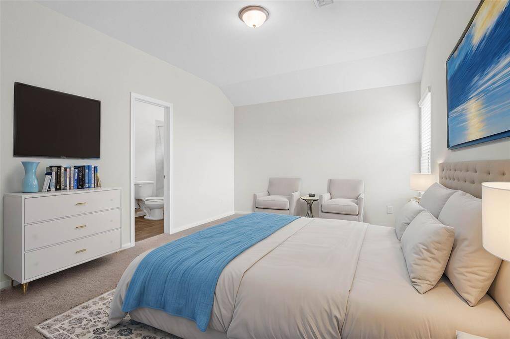 Secondary bedroom features plush carpet, neutral paint, raised ceilings, closet space, large windows with blinds, and private access to a secondary bathroom. *virtually staged*