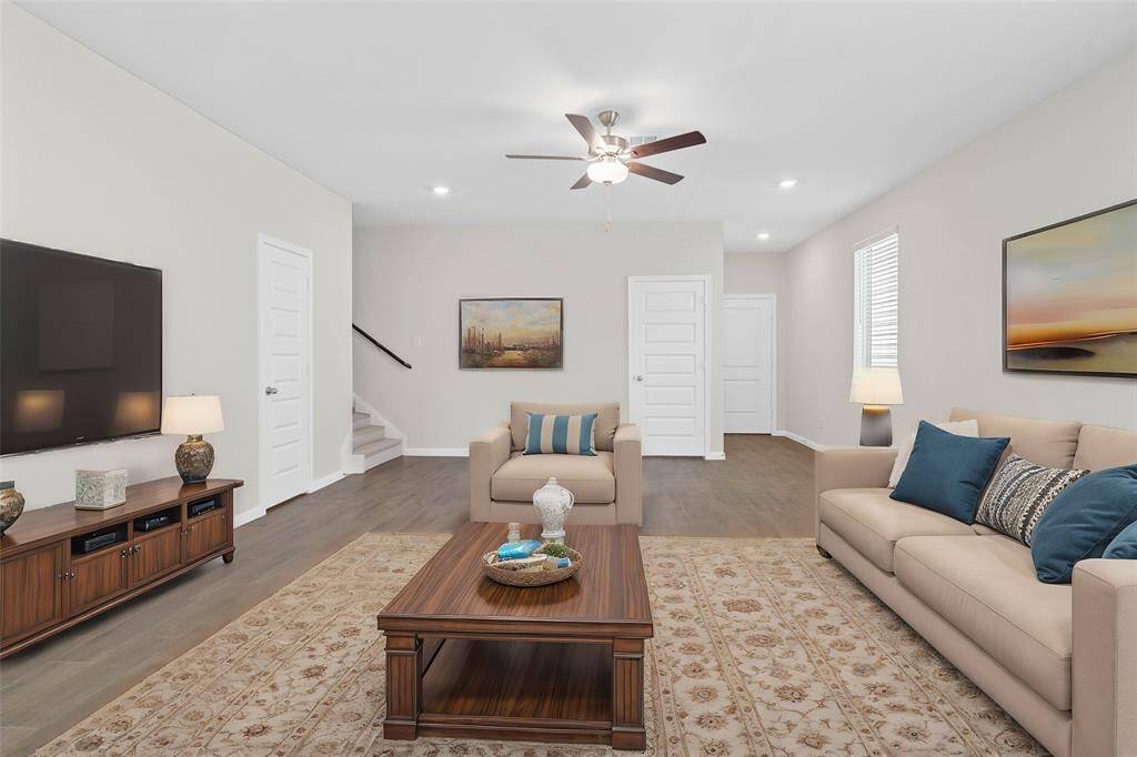 This living room is more like a GREAT room featuring high ceilings, wood look tile floors, recessed lighting, ceiling fan, and plenty of windows providing a natural light throughout the home. *virtually staged*