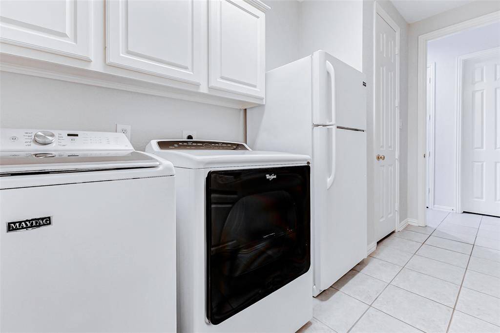 The other side of the laundry room features white cabinetry, a tile floor and a spacious layout with easy access to adjacent rooms.