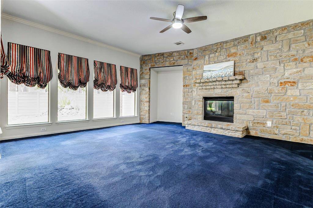 The living area features a striking stone fireplace, large windows providing ample natural light, and an inset for an entertainment area.