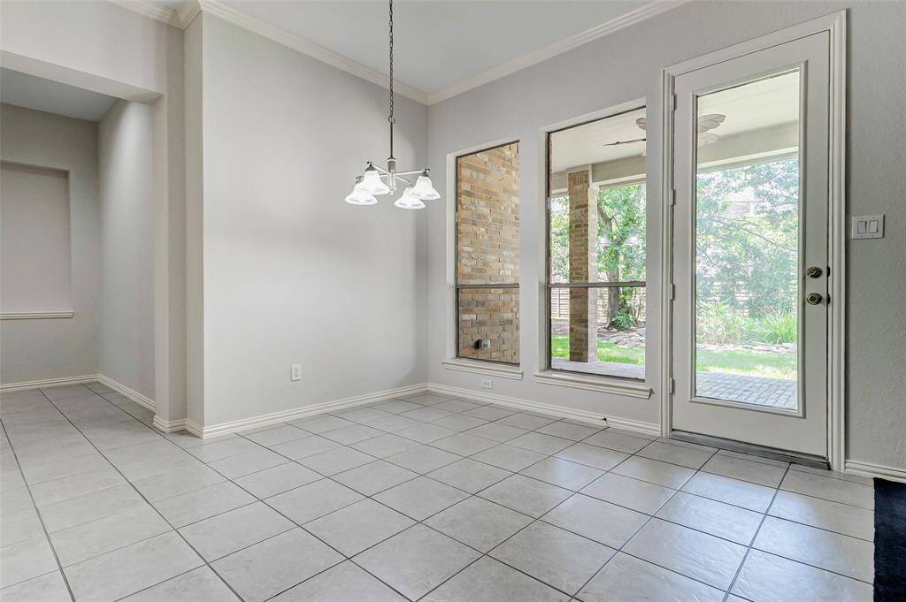 The bright breakfast area with large windows and a glass door leading to a covered porch, offers a view of the koi pond area.