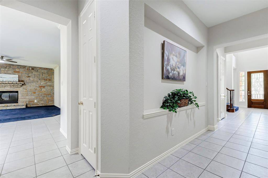 This bright entry hallway with tile flooring, leads to the living area and front door. The door leads to the 1/2 bath.
