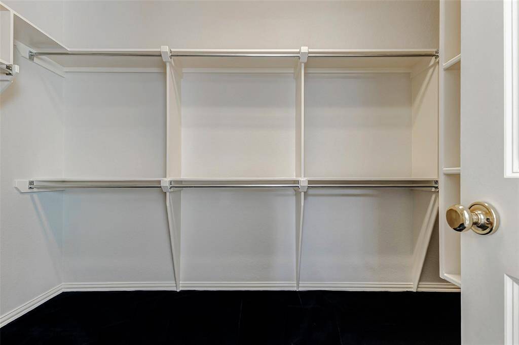 A spacious walk-in closet in the primary bath has multiple hanging rods and shelves, providing ample storage. The neutral color scheme and open design enhance its functionality and appeal.