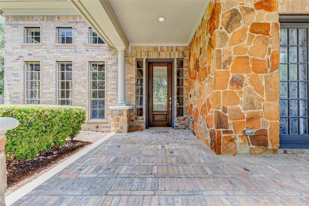 Welcome home to 22110 Stone Cross Court! This home showcases a welcoming front porch with elegant stone and brickwork, tall windows, and a solid wooden door.