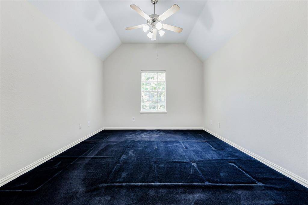 This is another secondary upstairs bedroom with high ceilings, a ceiling fan, and a window allowing natural light.