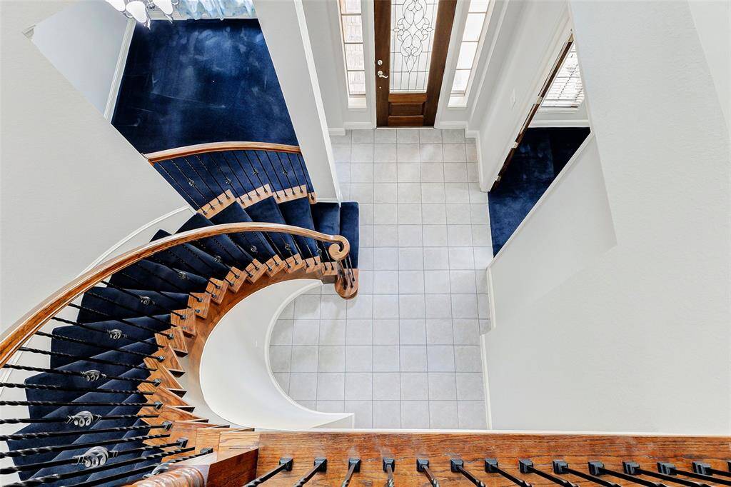 This photo showcases an elegant entryway with a stunning spiral staircase leading to the front door and other living areas.