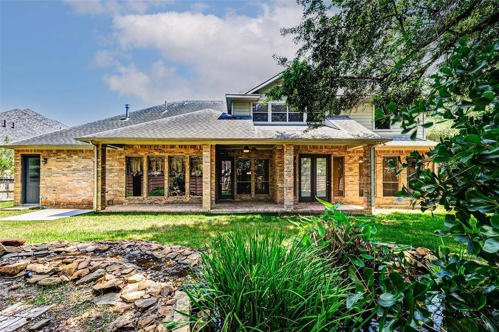 Another picture of the large backyard with a spacious covered patio. It features large windows and doors leading to a landscaped area with a  rock-bordered Koi pond. Ideal for outdoor relaxation and entertaining.