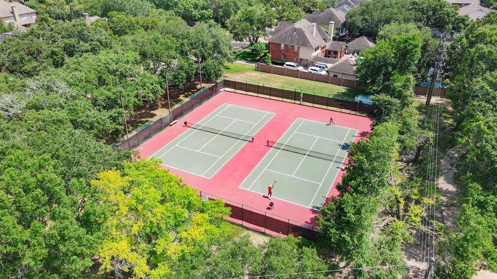 This is one of the spacious outdoor tennis courts surrounded by lush greenery, providing a serene environment for recreation. There are also pickleball courts nearby.