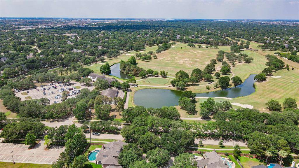 This aerial photo showcases the Cinco Ranch  golf course featuring ponds and well-maintained fairways. Residential homes surround the area, offering a peaceful and picturesque setting ideal for golf enthusiasts and those seeking a serene environment.