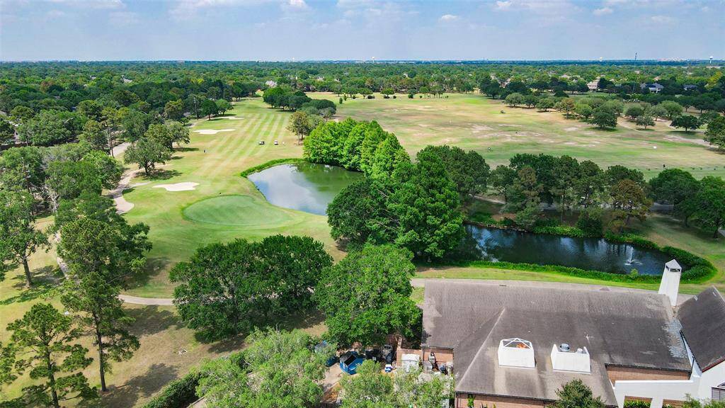 This aerial photo showcases a serene golf course view, featuring lush green fairways, sand traps, and a tranquil pond. The surrounding area is filled with mature trees, providing a picturesque and peaceful setting ideal for golf enthusiasts and nature lovers.