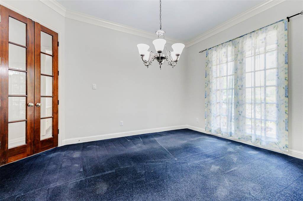 The dining room features elegant French doors, and a classic chandelier. Large windows allow natural light to fill the space, creating a bright and friendly atmosphere.