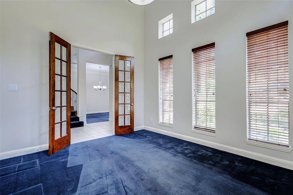 The office/study features tall windows with wooden blinds, and elegant French doors. The tall ceilings and transom windows allow for natural lighting to illuminate the room!