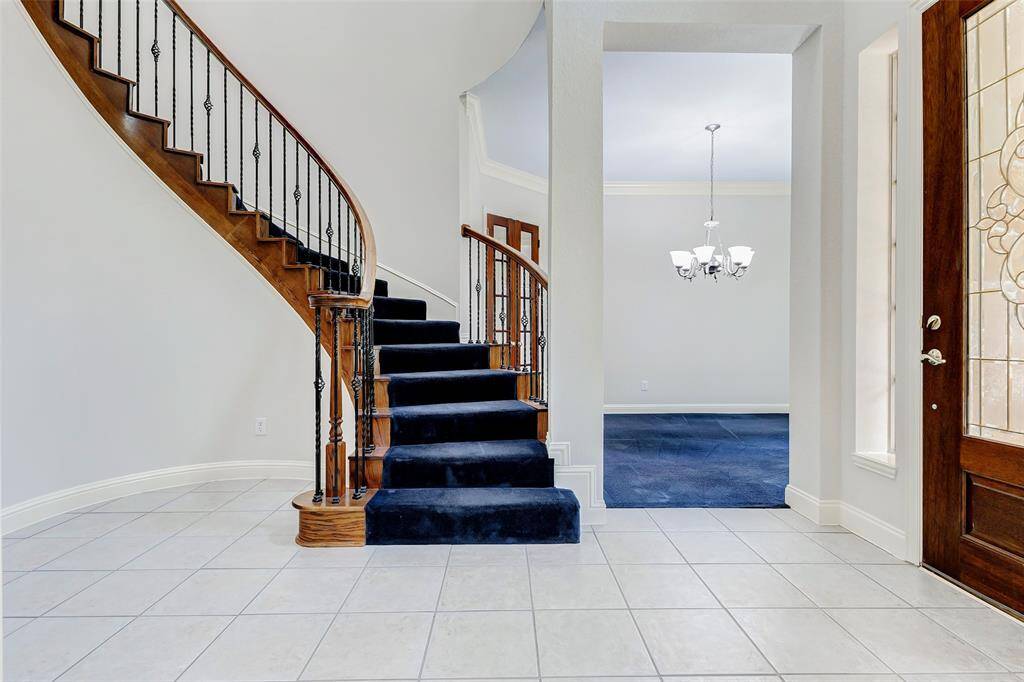 This elegant entryway features a curved staircase leading to the second floor.