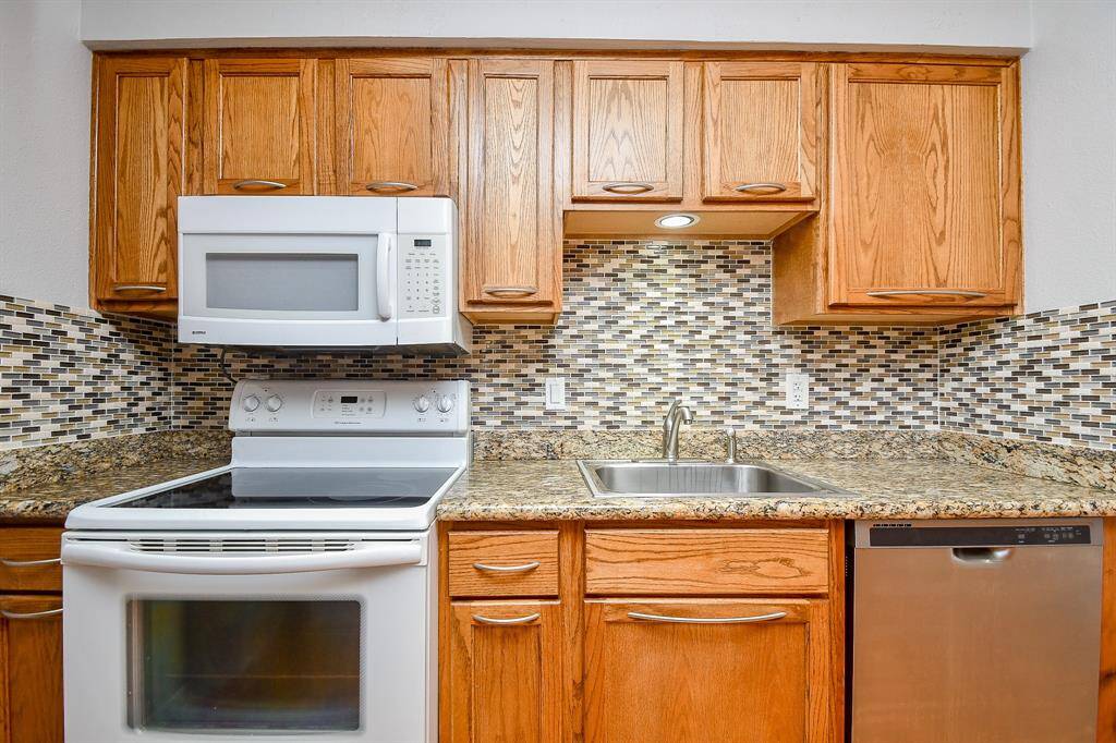 The granite counter, designer back splash and wood cabinets add style to the kitchen area.