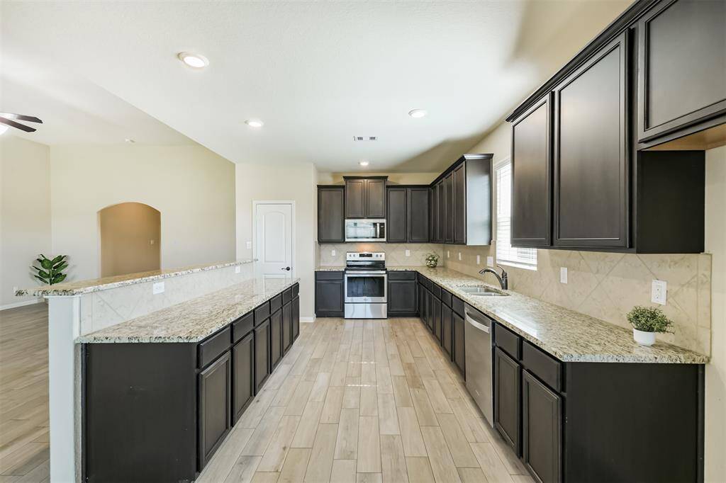 This kitchen boasts ample cabinets for all of your storage needs, along with granite counters, wood look tile, and stainless appliances.
