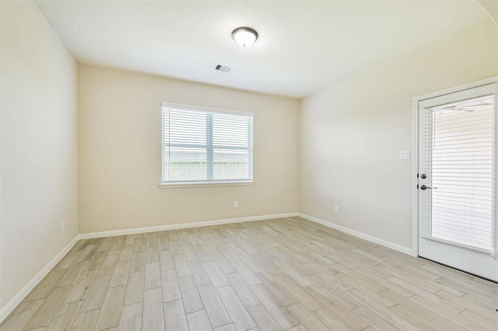 Dining room with wood look tile opens to the covered back porch.