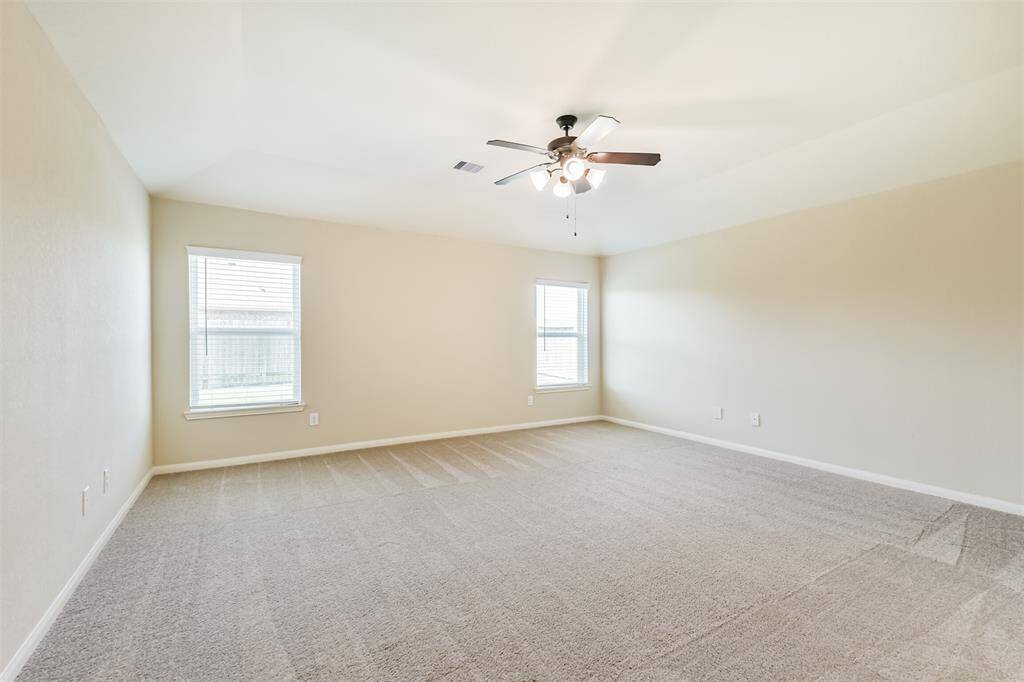 Primary bedroom with ceiling fan looks to the private backyard.