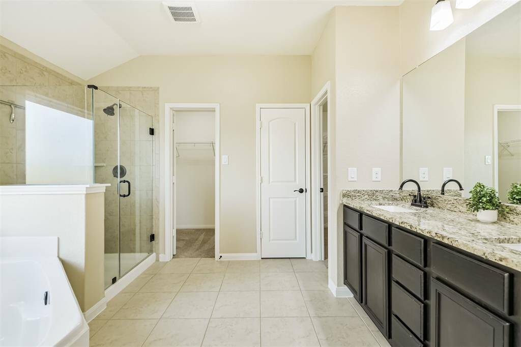 Primary bath with double sinks, soaking tub, frameless separate shower, linen closet, and large walk-in closet.