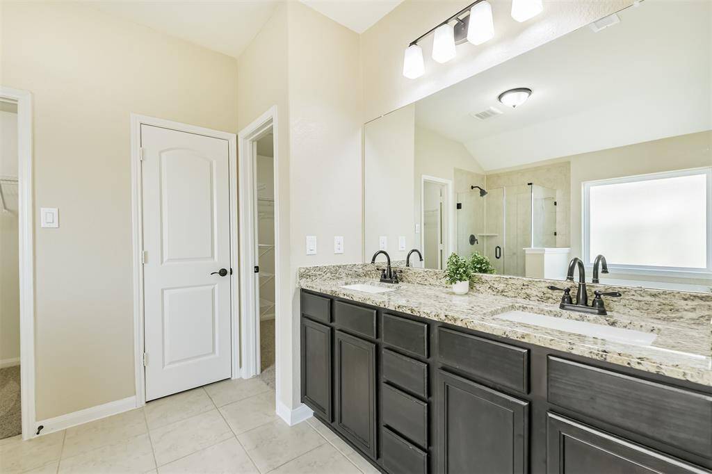 Double sinks with granite counters, bronze fixtures, and ample storage