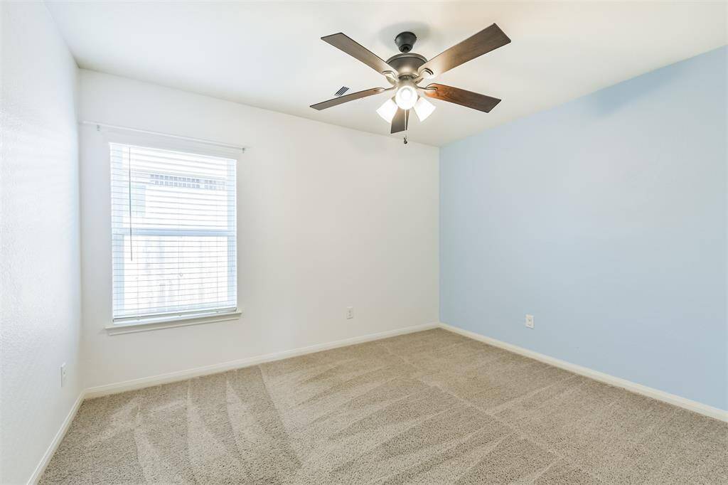 Second bedroom with ceiling fan and accent wall.