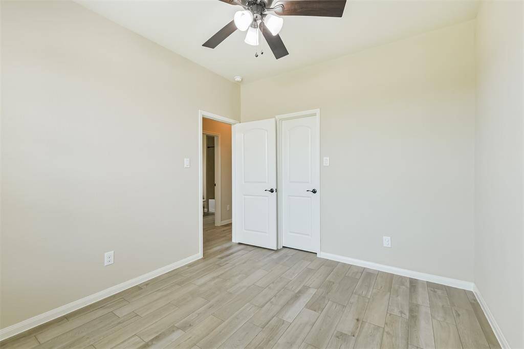 Fourth bedroom used as a study with walk-in closet, ceiling fan, and wood look tile.