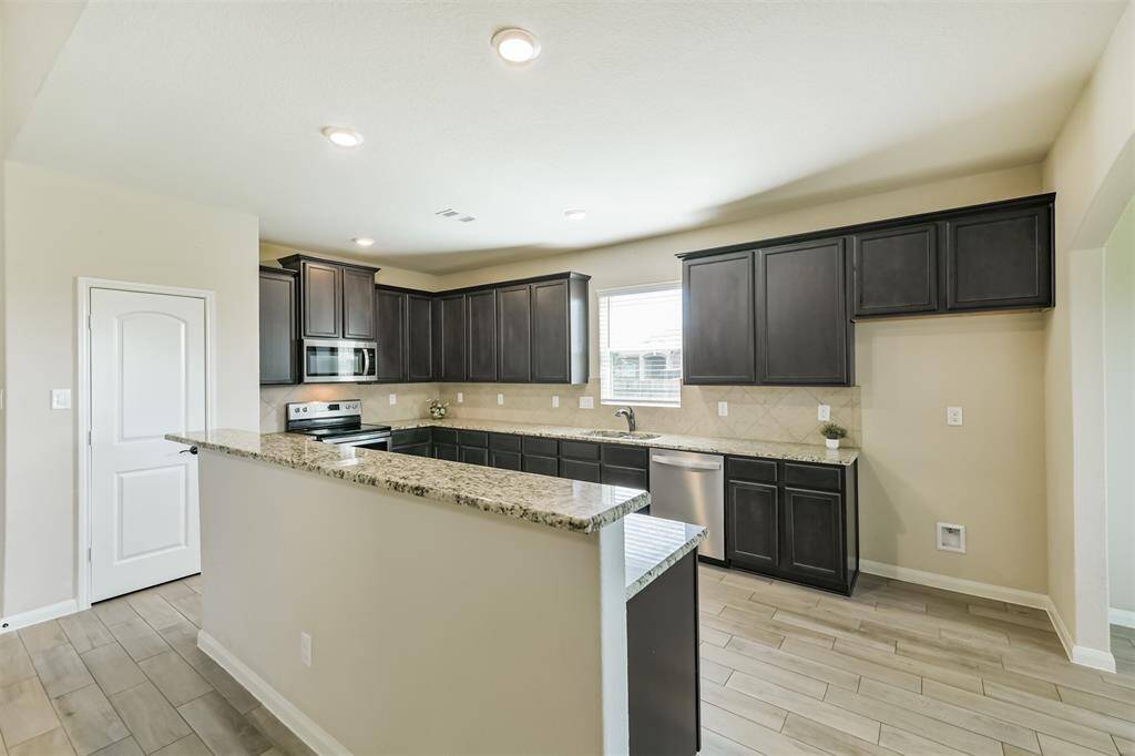 Large kitchen with granite counters, island with breakfast bar, pantry, and window over the sink.