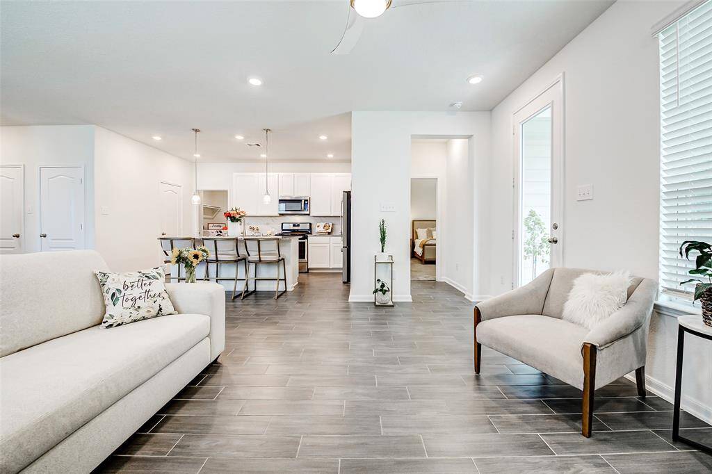 Open sight-lines to the kitchen, living and dining rooms keep the energy flowing throughout the space. Sneak peek at the primary bedroom down the hallway on the right.