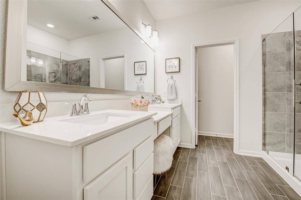 The en suite bathroom is impressive, offering a spa-like experience with a spacious walk-in shower, double sinks, a dedicated vanity area, a linen closet, and even extra storage tucked away in the water closet.