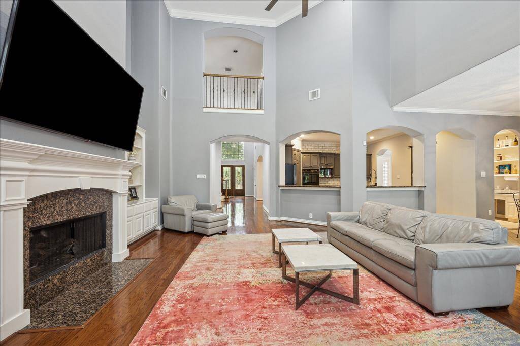 Open Concept Living for Everyday Life: Arched walkways, wood floors, and clear sightlines create effortless flow between the living room, kitchen, downstairs, and upstairs spaces.