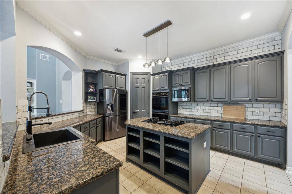 Updated Kitchen with Storage for Days: Freshly painted cabinetry, granite countertops, and updated hardware complement the travertine backsplash that runs to the ceiling.