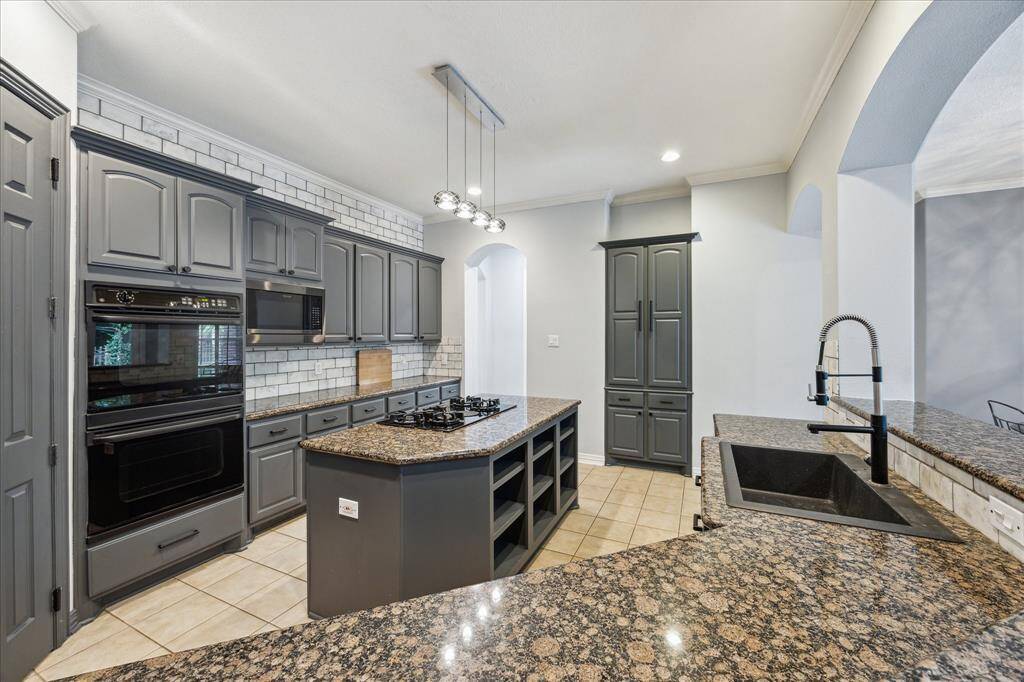 Storage-Rich Island & Everyday Functionality: A spacious center island with open shelving pairs with wall-to-wall cabinetry, a double oven, and an eat-up breakfast bar—designed for effortless prep, casual dining, and seamless flow.