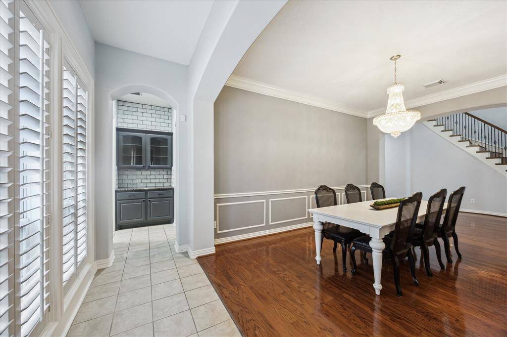 Dining Room with Direct Butler’s Pantry Access: A custom arched entry leads into the butler’s pantry—featuring granite countertops, painted cabinetry, and travertine backsplash to the ceiling.