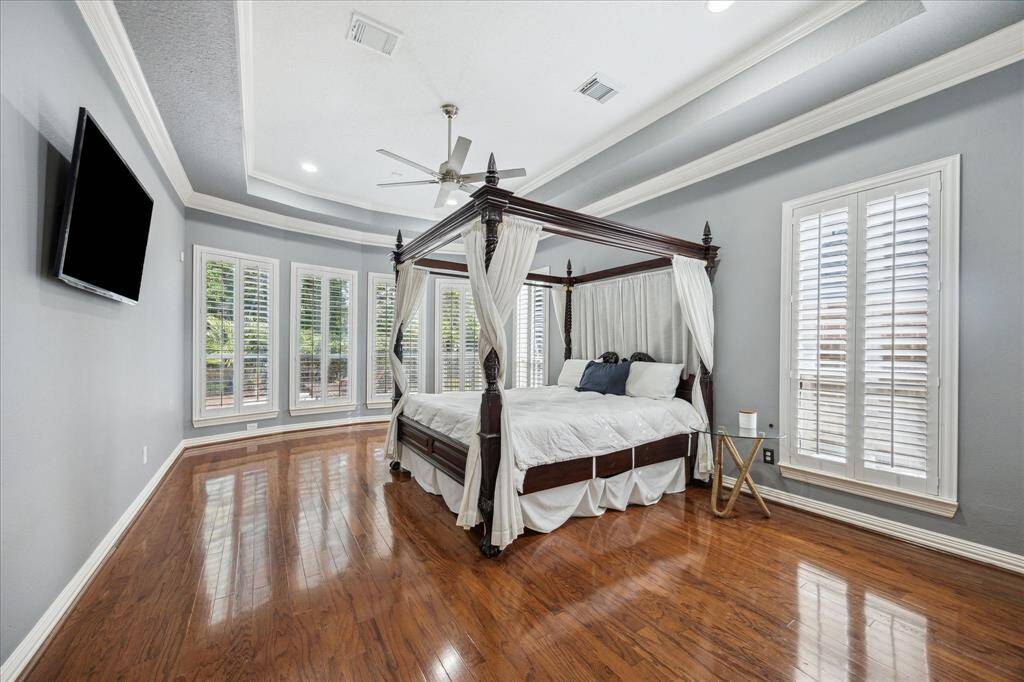 Retreat-Worthy Primary with Nature Views: Wood floors, tray ceilings, crown molding, and a full wall of windows overlooking the pool and preserve create a truly serene escape.