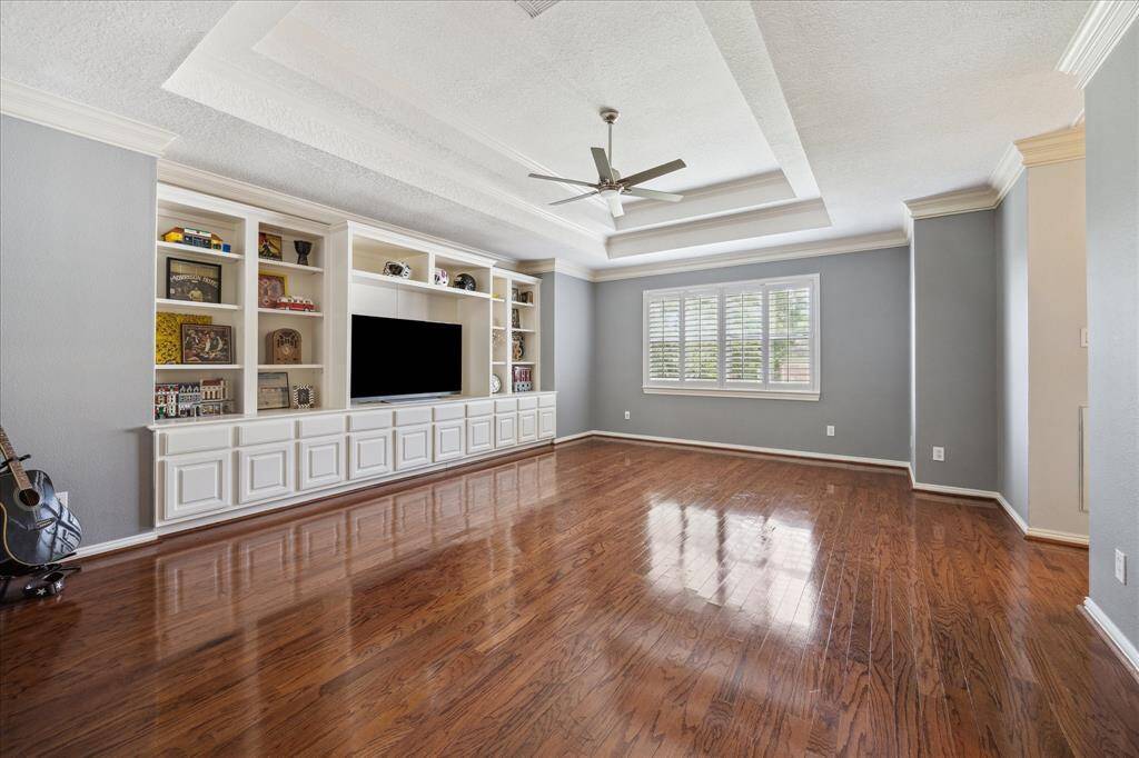 Expansive Game Room with Built-Ins: This oversized upstairs retreat features a full wall of built-ins, rich wood floors, coffered ceilings with triple crown molding, and is wired for sound—ready for game night or movie marathons.