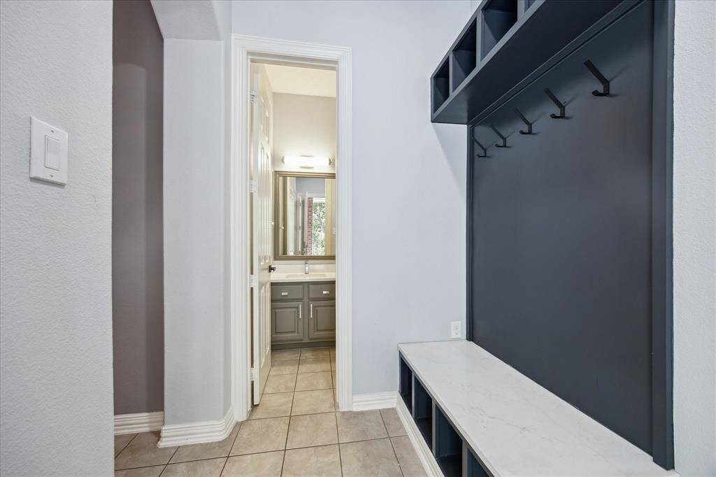 Stylish Storage Where You Need It: This updated drop zone includes custom hooks, cubbies, and access to one of two fully renovated half baths—this one just steps from the pool, and another off the main living room for guests.
