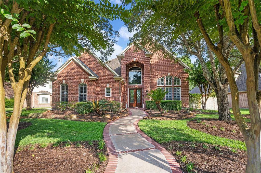 Brick-Lined Path to a Grand Entry: A winding walkway and mature landscaping create a picture-perfect arrival to the 8’ double doors and soaring entryway, setting the tone for the timeless design and quality finishes found throughout the home.