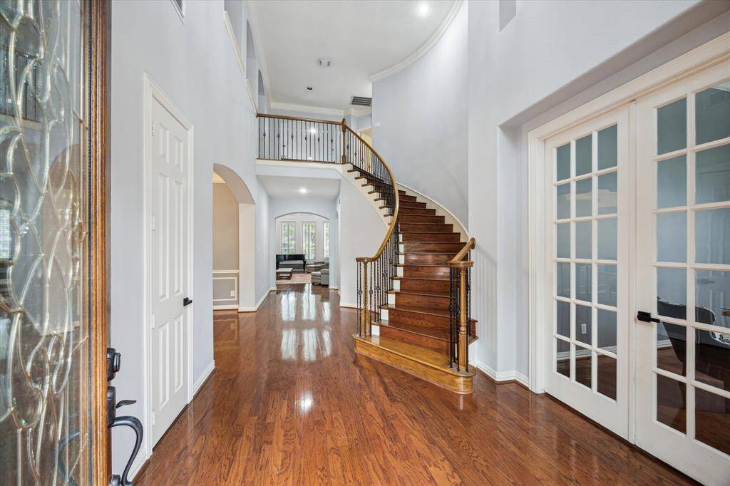 A Grand First Impression: The home’s curb appeal is matched by its impressive entry—thoughtfully designed to make a lasting impression. A sweeping curved staircase, soaring ceilings, and rich wood floors set the tone from the moment you step inside.