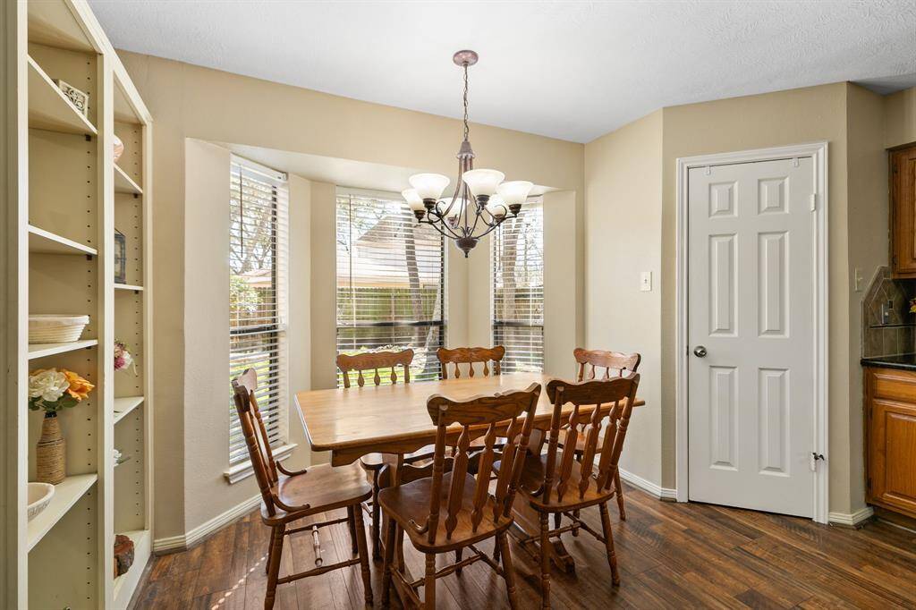 Adjacent to the family room and connected to the kitchen is a comfy breakfast nook with a wall of windows that looks out to the backyard. The door to the right is a walk-in pantry. On the left is a built-in display case which separates the breakfast area from the family room, adding both functionality and storage