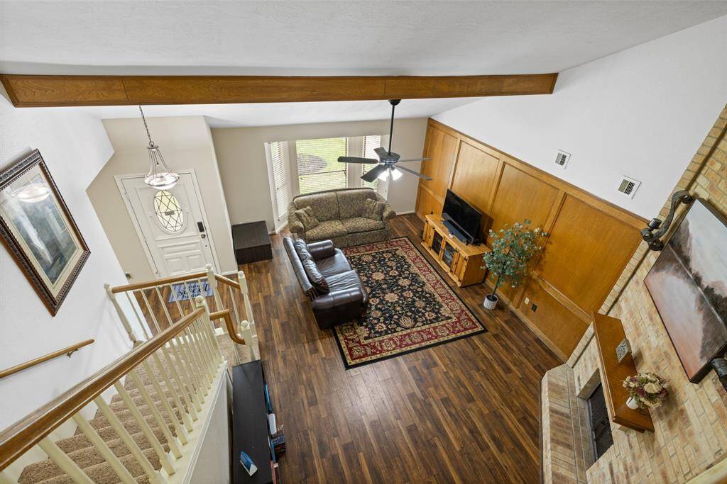 Looking down from the upstairs hallway, you have a clear view of the spacious living room below. It is highlighted by a wood beam that stretches across the room, adding character.