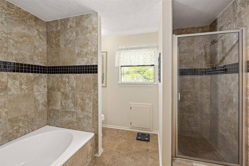The separate shower, located across from the tub, features the same black accent tiles, creating a cohesive look in the bathroom. Whether your enjoy a relaxing soak in the tub or a hot, refreshing shower, you get to choose